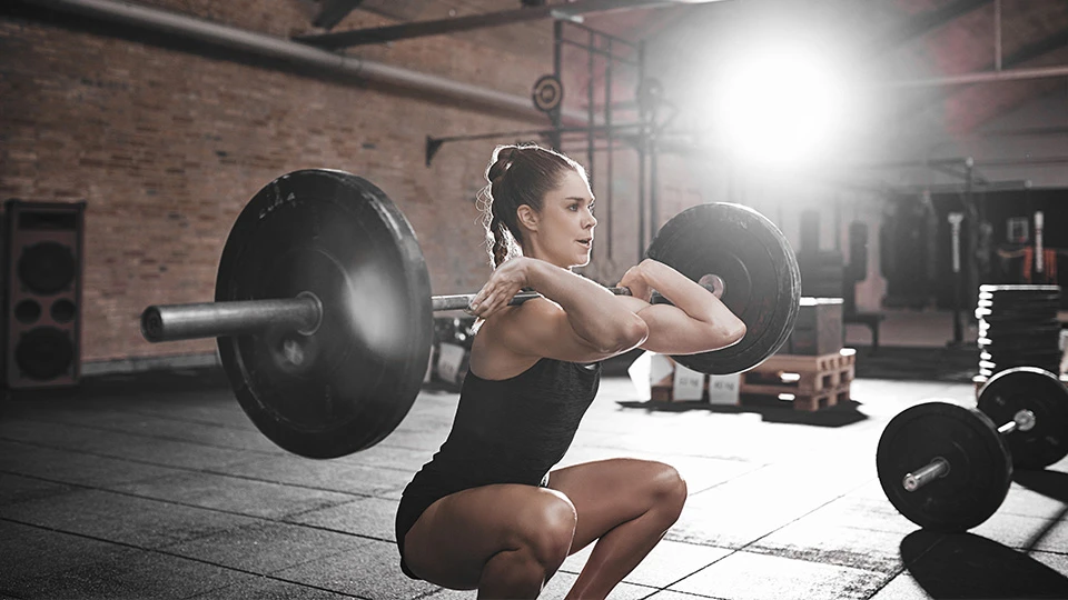 Woman Squatting Olympic Weights in a Gym